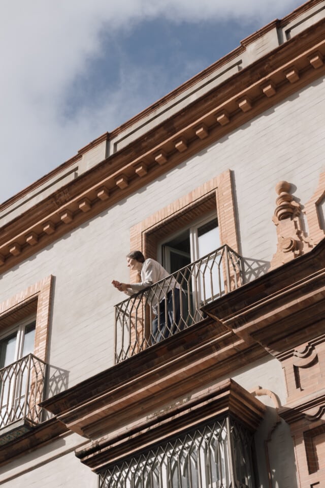 Una persona se asoma a uno de los balcones bañados por el sol del hotel boutique Plácido y Grata en Sevilla.